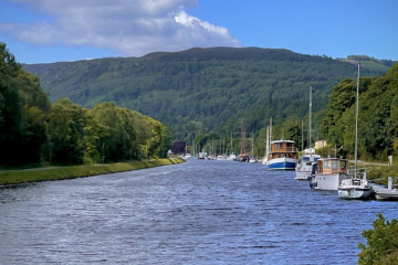 Caledonian Canal with boats moored on the right side of the waterway. 