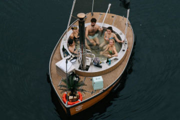 Friends enjoying a self-guided Hot Tub Boat tour in Berlin, soaking in warm water as they explore the river near Treptower Park and the Oberbaumbrücke. A fun, social and memorable way to discover the city together.