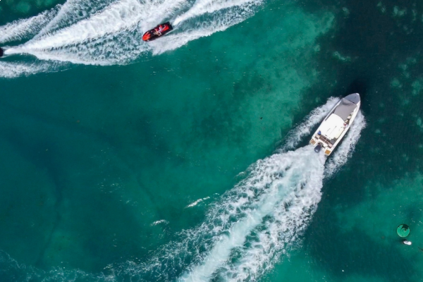 A sleek speedboat gliding across crystal-clear waters during an RYA Powerboat Level 2 course, showcasing practical training sessions amidst stunning coastal scenery.
