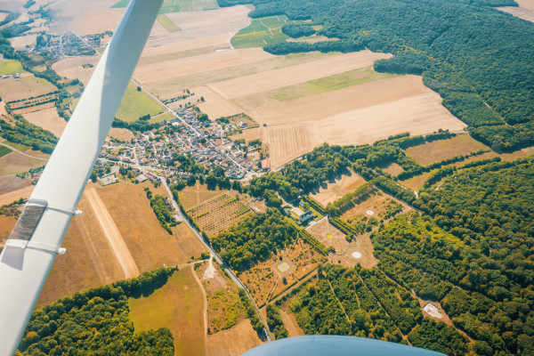Seen from the sky aboard the single-engine aircraft, we observe a village and a park and its castle about 3500m high.