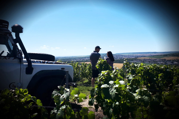 Defender on the left and in the center a couple in the vineyards of the 1 cru glass of champagne in hand