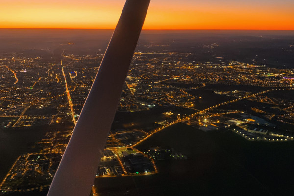 On board the single engine plane, sunset, the sky is orange and black we observe the city of Reims at about 3500m high.