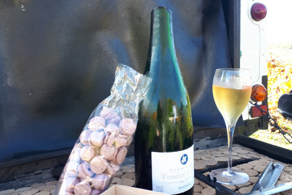 Bar of the open vehicle, a bottle of champagne already sliced, champagne is served. Cupcake and meringue with pink biscuit in service.