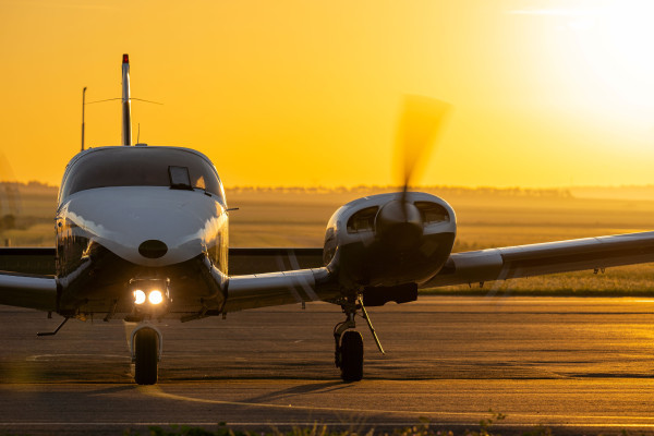 Sunset, twin engine aircraft on runway, propellers turning
