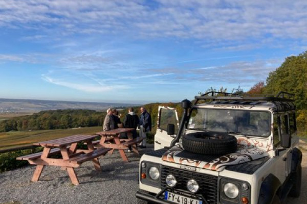 Tasting in the vineyard, people are in front of the vineyards with a glass of champagne seen on Epernay, the Defender is in the foreground.