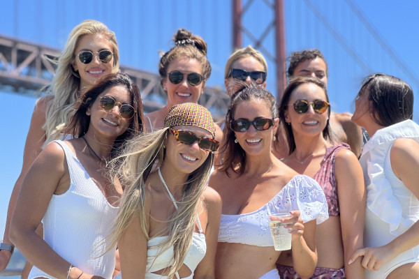 a group of beautiful ladies dressed in white smiling and having fun on a boat aprty