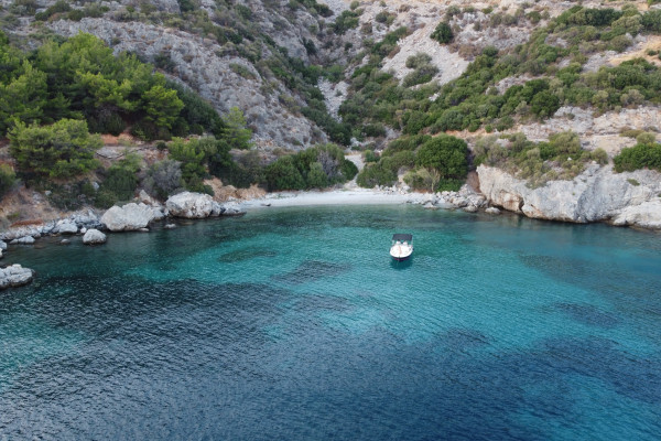 The boat is anchored in a bay during sunset time and two persons are laying in the front of the boat.
