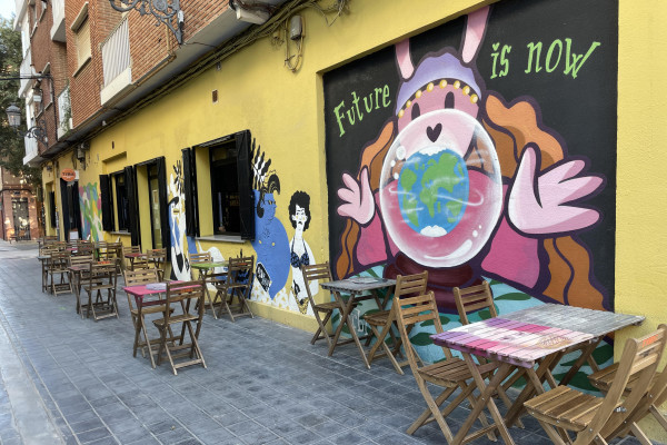 A quiet street corner featuring a mix of vibrant graffiti and restored historic homes.