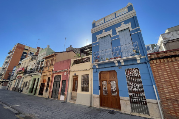 A picturesque street lined with low fishermen's houses and vibrant ceramic patterns in Valencia's maritime district.
