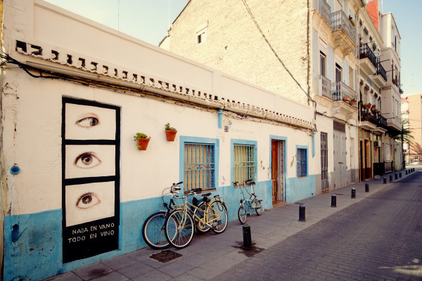 Bicycles on a sunny, mural-lined street in El Cabanyal.