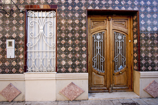 A beautifully aged wooden door with ceramic details on a house in El Cabanyal.