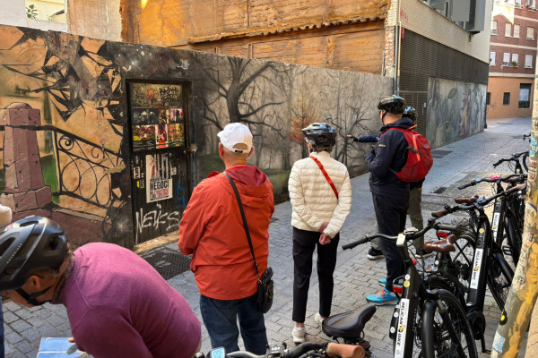 Cyclists stopped with their bikes in front of an urban mural while the guide describes its details