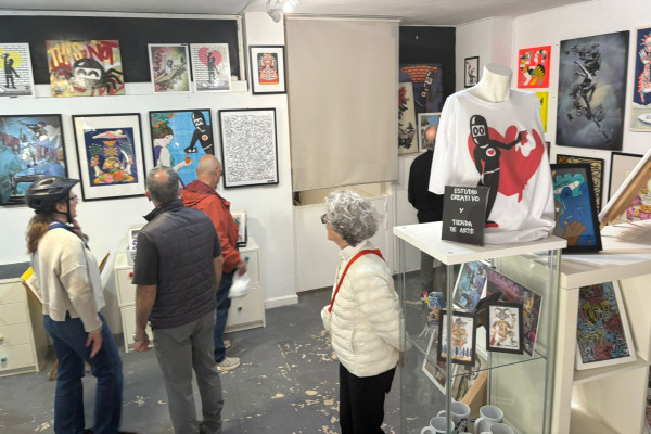 Cyclists exploring a small urban art gallery filled with framed street art prints and illustrations