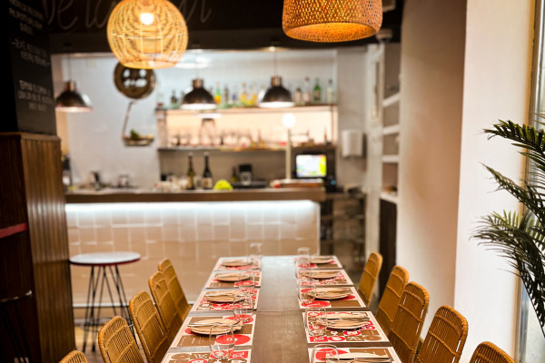 Large wooden table set for guests with woven chairs and warm hanging lamps in a traditional Valencian restaurant
