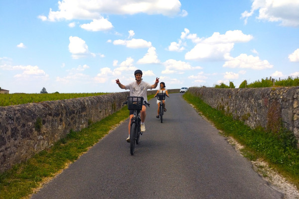 Cyclists riding through authentic Bordeaux vineyard roads.