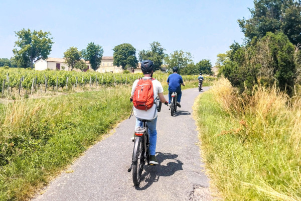 Cyclists riding through authentic Bordeaux vineyard roads.
