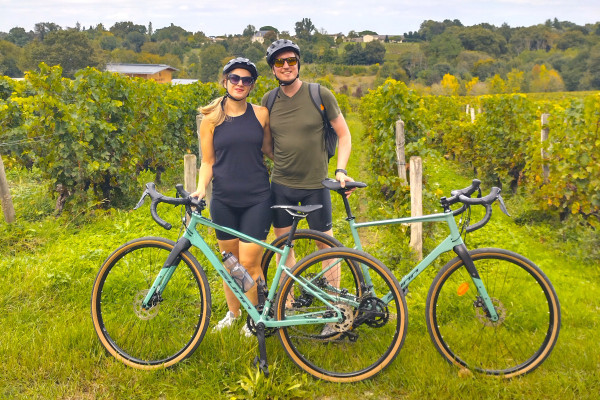 Small group riding gravel bikes between rows of vines.
