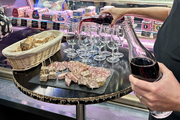 Tasting of local charcuterie with a glass of Beaujolais red wine during a food tour at Les Halles Paul Bocuse