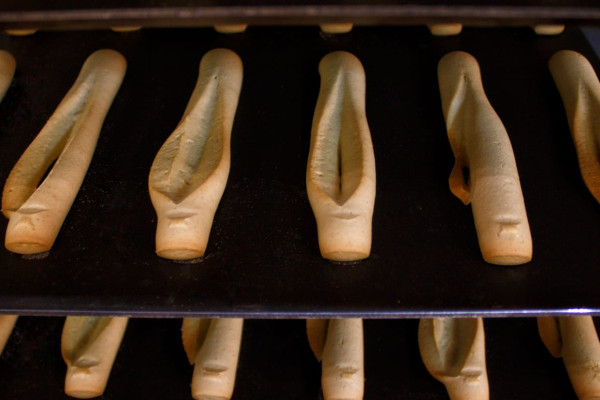 Provençal navettes baking, lined up in an artisanal biscuit shop in the South of France.