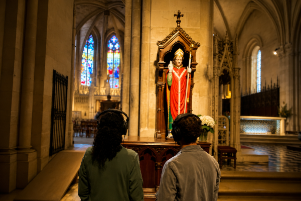 A couple immersed in an audio journey, discovering the story of Saint Seurin before his statue.
