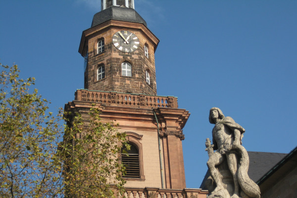 Brunnenfigur Siegfried im Vordergrund des Turms der Dreifaltigkeitskirche
(Treffpunkt der Tour)