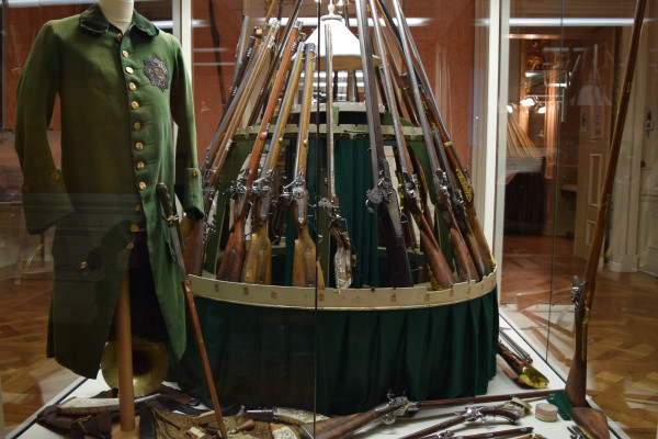 Vitrine mit Pirschrock und Jagdwaffen.