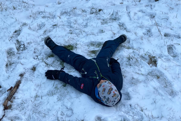 Kind macht einen Schneeengel im Schnee