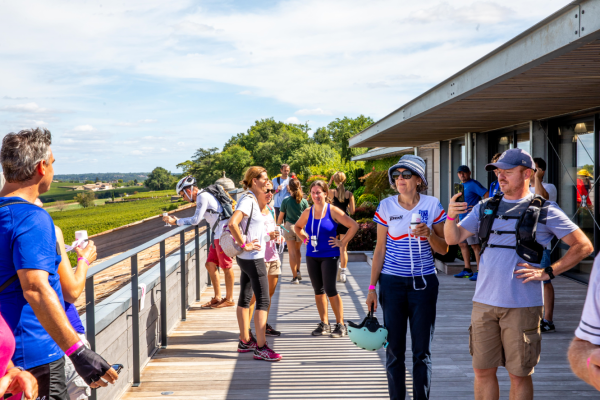 Groupe de visiteurs dégustant du vin rouge sur la terrasse du Château Balestard La Tonnelle