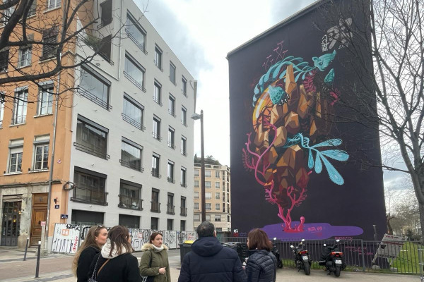 Le groupe est devant une grande peinture murale 