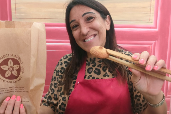 Une artisan passionnée de biscuits provençaux montrant avec une pince les macarons de Provence.