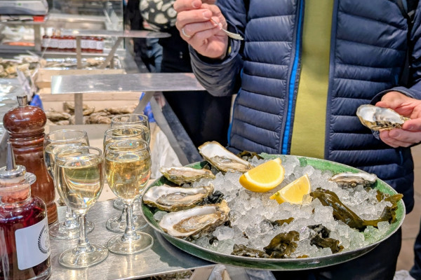 Dégustation de fruits de mer de saison crevettes et huîtres accompagnés d'un verre de vin blanc de la région lors d'un Food Tour aux Halles Paul Bocuse